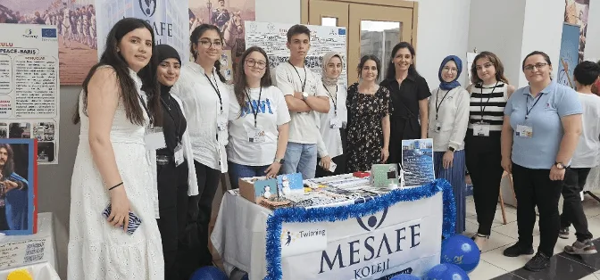 Mesafe Koleji masasının başında e-Twinning yıl sonu yaygınlaştırma sergisine katılan öğrenci ve öğretmen grubu