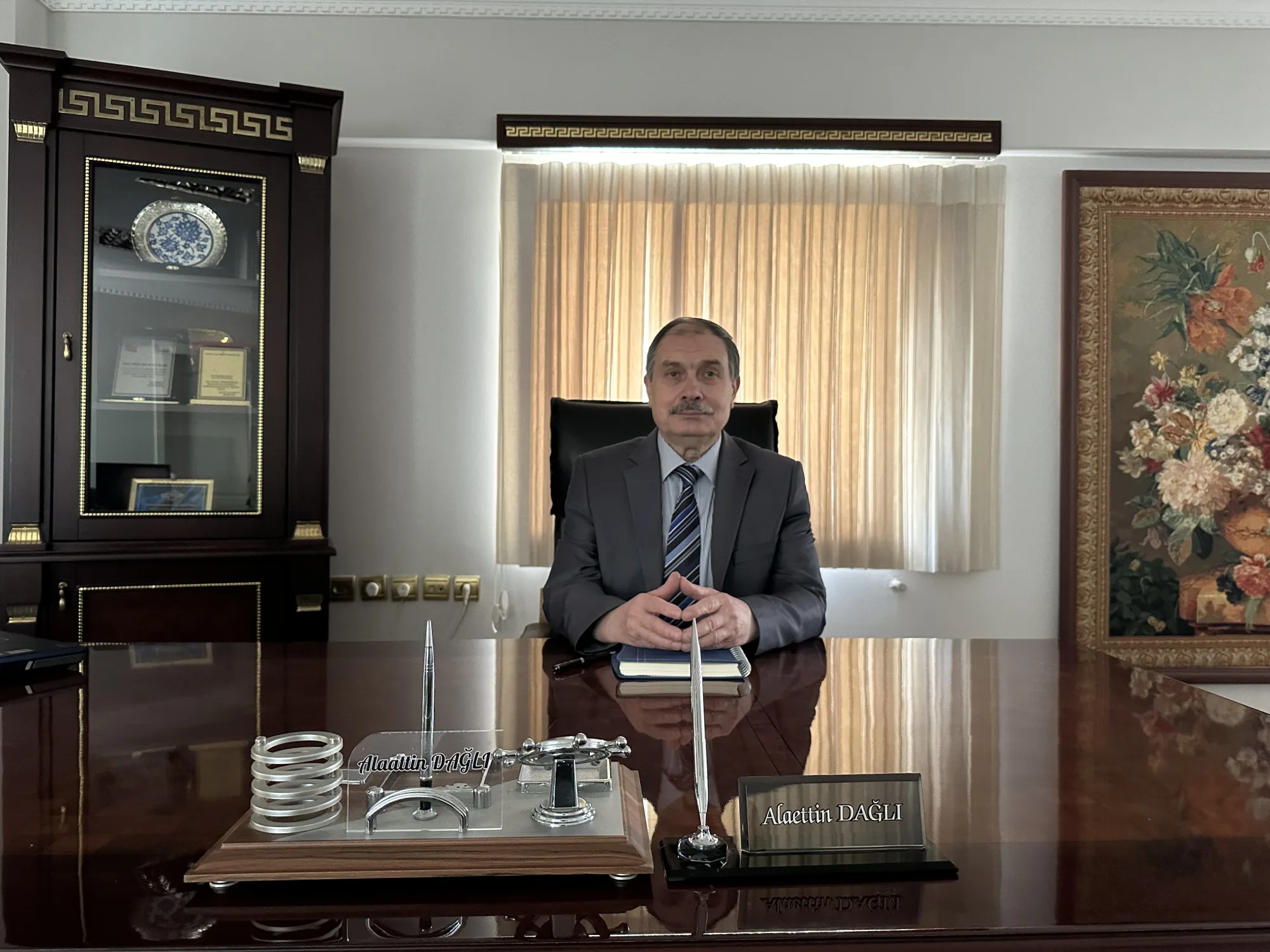 Alaettin Dağlı, kurucu portresi (masa üstü isimlik görünür)