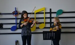 Keman kulübü öğrencileri sahnede keman çalıyor