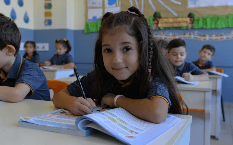 İlkokul öğrencisi sırada kitabına yazı yazıyor